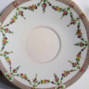 May include: A white ceramic cake plate with a gold and brown lattice border and a floral design. The plate has two handles.