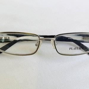 May include: Silver-rimmed spectacles with clear lenses. The frames have a rectangular shape with black and white patterned arms. The brand name "PLAYLIFE" is printed on the right lens.