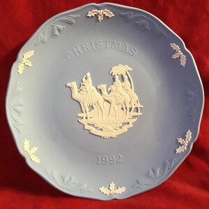 Könnte beinhalten: Ein blauer und weißer Keramik-Weihnachtsteller mit einem weißen Relief-Design der drei Weisen, die auf Kamelen reiten. Der Teller trägt die Aufschrift "Christmas" und das Jahr "1992".