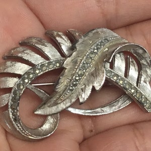 Spilla vintage P101 a forma di sfinge, firmata, in metallo argentato con foglia e pietra di marcasite. Spedizione tracciabile.