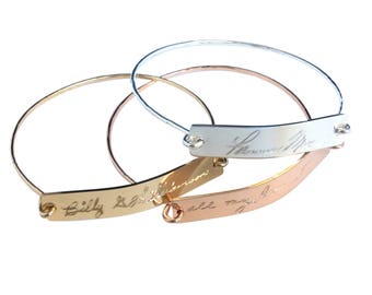 May include: Three gold bangle bracelets with personalized engraved messages. The bracelets are stacked on top of each other. The top bracelet is silver and engraved with the text "I love you Mom". The middle bracelet is gold and engraved with the text "Billy & Allison". The bottom bracelet is rose gold and engraved with the text "all my love".