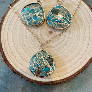 May include: A gold chain necklace and matching earrings with turquoise and gold teardrop-shaped pendants. The pendants have a marbled pattern.