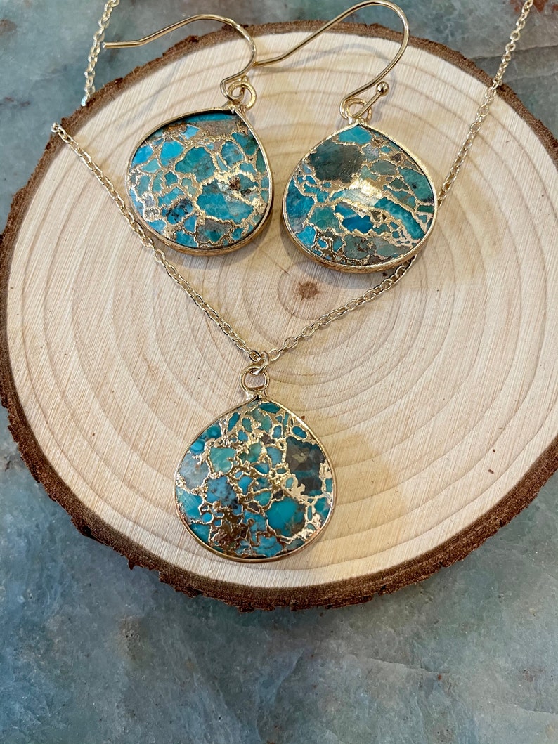 May include: A gold chain necklace and matching earrings with turquoise and gold teardrop-shaped pendants. The pendants have a marbled pattern.