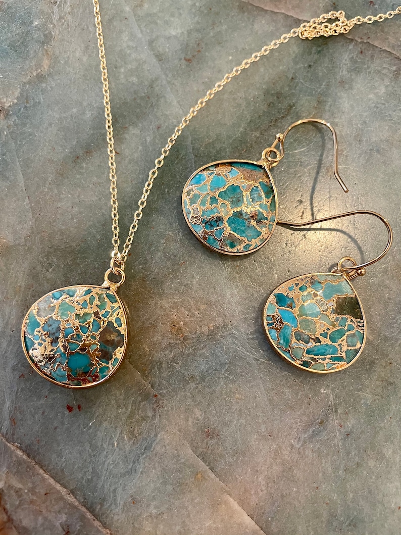 May include: A gold chain necklace and matching earrings with turquoise and gold teardrop-shaped pendants.