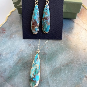 May include: A turquoise and brown teardrop-shaped pendant necklace and matching earrings. The jewelry is made with gold-toned metal.