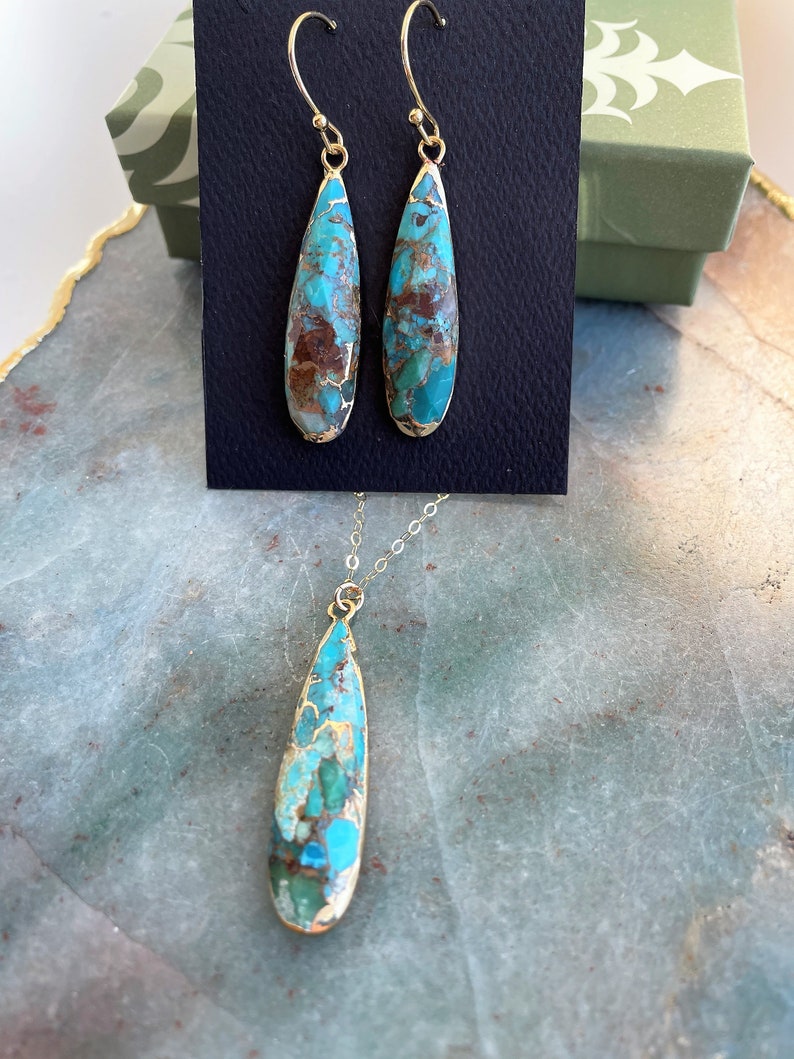 May include: A turquoise and brown teardrop-shaped pendant necklace and matching earrings. The jewelry is made with gold-toned metal.