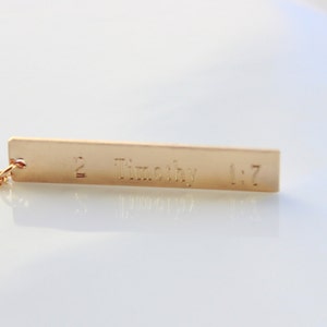 May include: Gold necklace with a rectangular pendant that says "2 Timothy 1:7".
