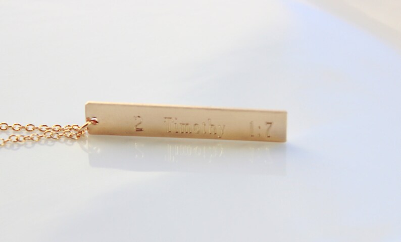 May include: Gold necklace with a rectangular pendant that says "2 Timothy 1:7".