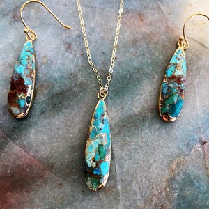 May include: A turquoise and brown teardrop-shaped pendant necklace and matching earrings. The jewelry is made with gold-toned metal.