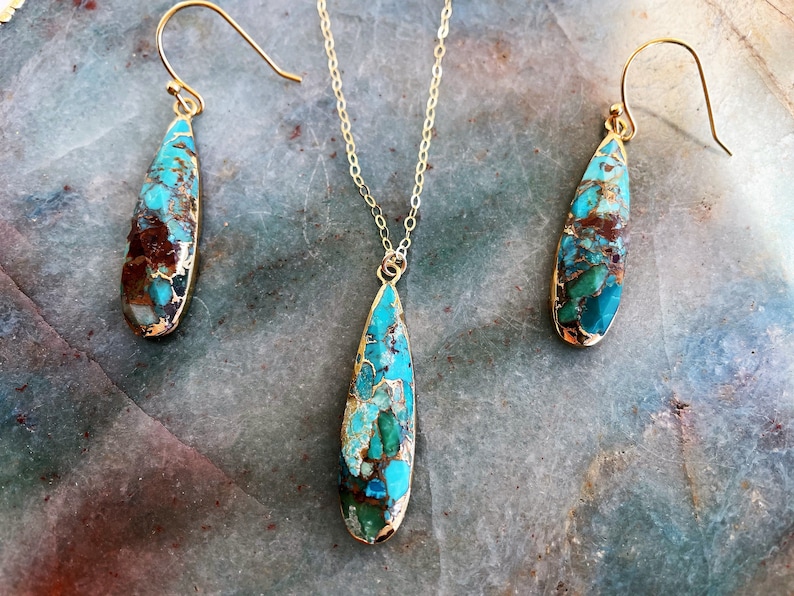 May include: A turquoise and brown teardrop-shaped pendant necklace and matching earrings. The jewelry is made with gold-toned metal.