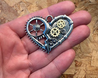 May include: A silver and gold heart-shaped pendant with a steampunk design featuring gears and cogs.