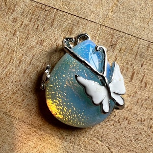 May include: A silver charm with a blue iridescent glass teardrop shape and a white butterfly design.