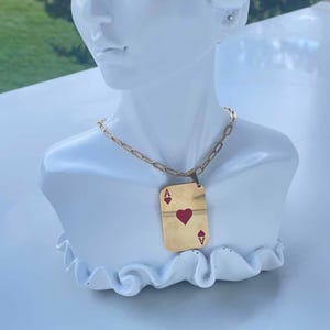 Collier en acier inoxydable doré, accompagné d'un pendentif représentant un jeu de cartes.
