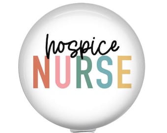 May include: White round badge holder with a retractable cord and a clear plastic clip. The badge has the text "hospice NURSE" in black with the word "NURSE" in rainbow colors.