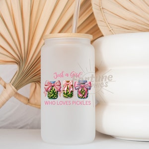 Op de afbeelding: Een witte, gematteerde glazen beker met een bamboe deksel en een rietje. De beker heeft een roze afbeelding van drie augurkenpotten met roze strikken en de tekst "Just a Girl Who Loves Pickles".