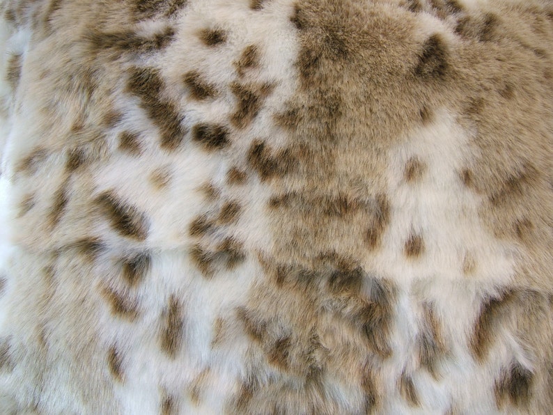 May include: Close-up of a white and brown faux fur fabric with a spotted pattern.