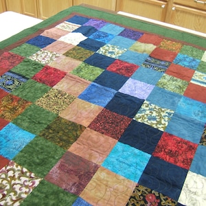 May include: A patchwork quilt with a variety of colors and patterns, including red, blue, green, and brown. The quilt is made up of squares of different fabrics, each with a unique design.