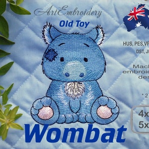 Könnte beinhalten: Maschinenstickerei-Design eines blauen Wombats mit einem Augenpflaster, der mit seinen Pfoten vor sich sitzt. Das Design ist in zwei Größen erhältlich: 4x4 Zoll und 5x5 Zoll.