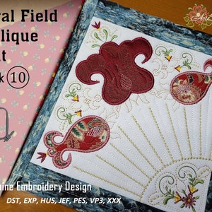 Op de afbeelding: Een wit vierkant van stof met een rood, groen en gouden bloemenapplicatiedesign. Het ontwerp heeft een paisley-patroon en een zonnestralen. De tekst "Floral Field Applique Quilt Block (10)" is zichtbaar in de linkerbovenhoek. De tekst "Machine Embroidery Design DST, EXP, HUS, JEF, PES, VP3, XXX" is zichtbaar in de linkerbenedenhoek.
