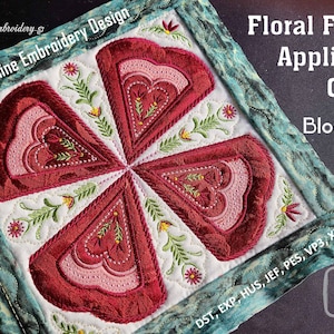 Peut inclure: Un bloc de quilt carré avec un motif floral appliqué. Le motif central présente quatre éléments en forme de cœur dans des tons de rouge et de rose, entourés de feuilles vertes et de fleurs jaunes. Le texte "Floral Field Applique Quilt Block 8" est visible.