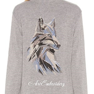 May include: Grey long-sleeved shirt with an embroidered wolf design on the back. The wolf is facing to the right and has a blue, brown and white colour scheme. The text "Art Embroidery" is embroidered below the wolf.
