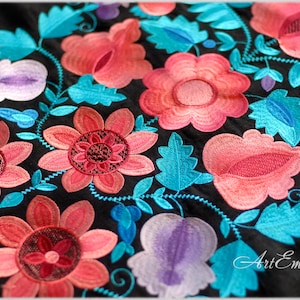 Puede incluir: Tela negra con flores bordadas de colores en tonos rosa, rojo, azul y morado. El bordado presenta un patrón floral con hojas y enredaderas.