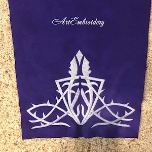 May include: A white embroidered design on a purple fabric background. The design features a stylized, geometric shape with a pointed top and a series of curved lines. The text "Art Embroidery" is visible at the top of the image.