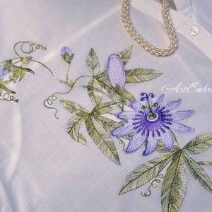Może przedstawiać: Biała koszula z haftowanym wzorem passiflorą w kolorze fioletowym i zielonym. W obrazie widoczny jest tekst "Art Embroidery".