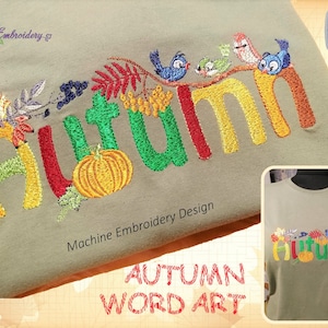 Op de afbeelding: Olijfgroen T-shirt met het woord "HERFST" geborduurd in kleurrijk garen. Het ontwerp bevat een pompoen, bladeren en vogels. De tekst "Art Embroidery Design" is ook zichtbaar.