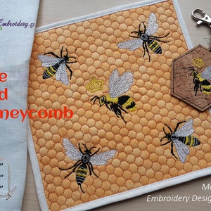 May include: A machine embroidery design set featuring a honeycomb pattern with embroidered bees. The set includes a square quilted design and a cork keychain with a bee design. The text "Bee and Honeycomb" is visible.