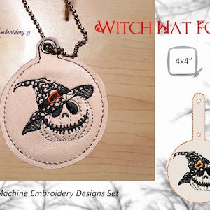 May include: A light pink Witch Hat Fob with a Jack-o'-lantern design. The design features a smiling skull wearing a black witch hat with an orange buckle. The fob is attached to a silver chain. The text "Witch Hat Fob" is displayed in red.