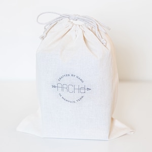 white drawstring bag with logo in the center