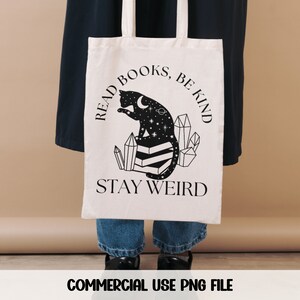 May include: A white tote bag with a black cat sitting on crystals and the text "Read Books, Be Kind, Stay Weird".