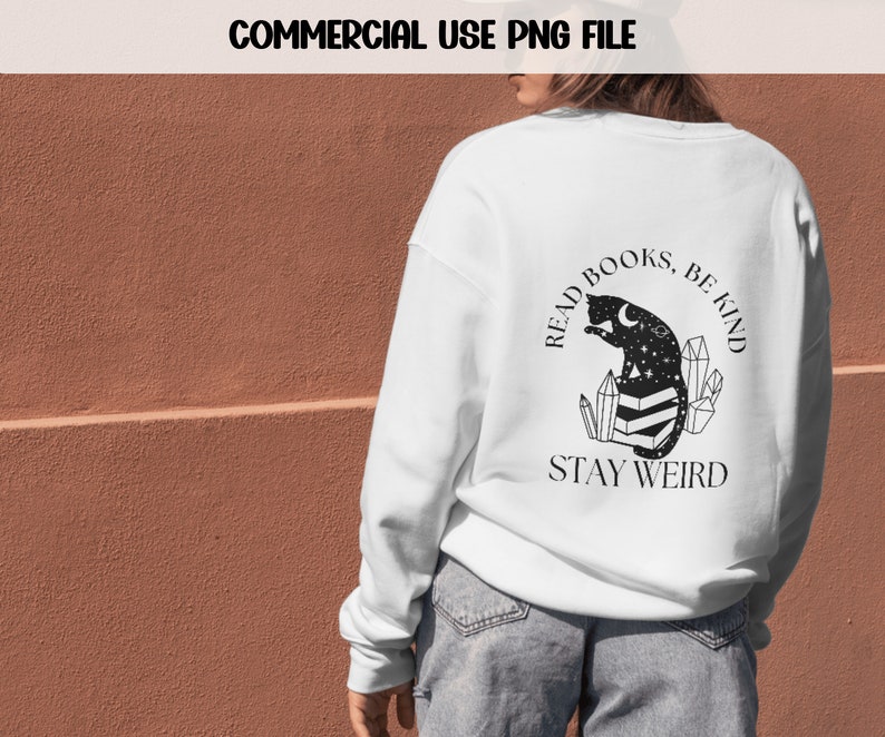 May include: White sweatshirt with a black graphic design featuring a cat reading a book with crystals and the text "Read Books, Be Kind, Stay Weird".