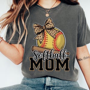 May include: A gray t-shirt with a softball, a bow, and the text "Softball Mom".