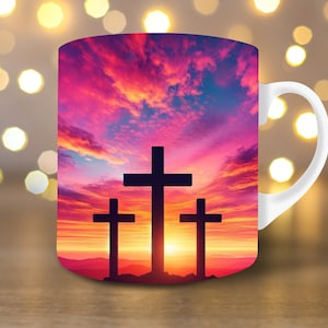 May include: White ceramic mug with a colorful sunset and three black crosses silhouetted against the sky.
