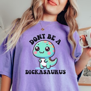 May include: Purple t-shirt with a cartoon dinosaur and the text "Don't be a Dickasaurus".