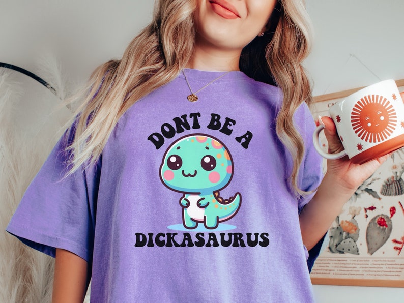May include: Purple t-shirt with a cartoon dinosaur and the text "Don't be a Dickasaurus".
