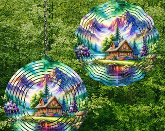 May include: Two metal wind spinners with a colorful mountain scene and a cabin by a lake. The spinners are circular and have multiple layers of metal.