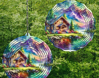 May include: Two metal wind spinners with a colorful design of a cabin in the woods by a lake. The spinners are round and have multiple layers of metal that spin in the wind.