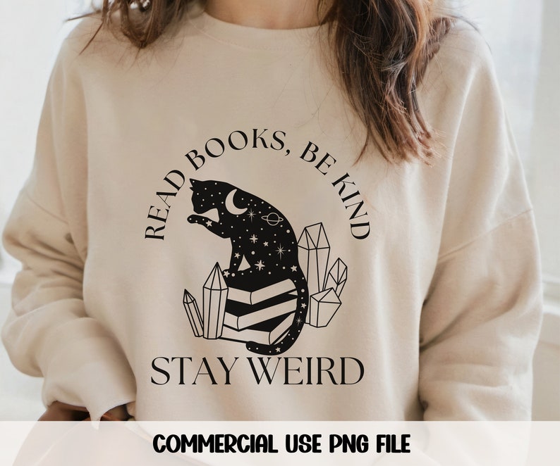 May include: A beige sweatshirt with a black graphic design featuring a cat sitting on a stack of books. The text reads "Read Books, Be Kind, Stay Weird".