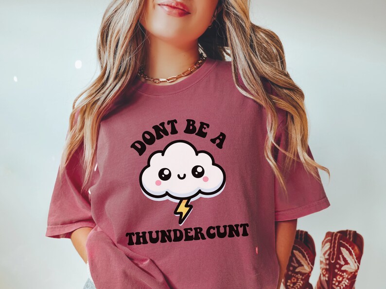May include: A pink t-shirt with a graphic of a cartoon cloud with a lightning bolt and the text "Don't be a Thundercunt".