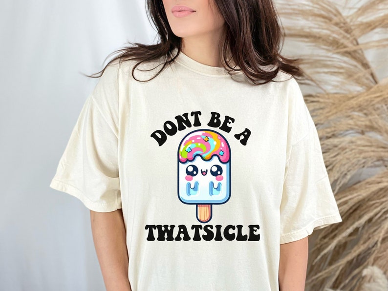 May include: A white t-shirt with a graphic of a cartoon popsicle with a rainbow swirl and the text "Don't be a Twatsicle".