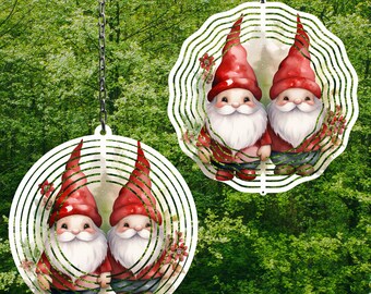 May include: Two white metal wind spinners with a circular design. Each spinner features two gnomes with red hats and white beards. The gnomes are surrounded by green leaves and flowers.