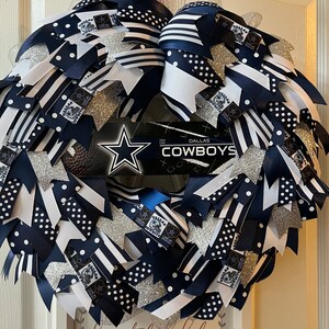Puede incluir: Una corona de Dallas Cowboys azul y blanca con purpurina plateada y lunares blancos. La corona est&aacute; decorada con una cinta de Dallas Cowboys y un logotipo de Dallas Cowboys.