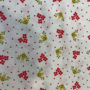 May include: White fabric with a repeating pattern of red flowers, green leaves, and yellow bees. The background is a white polka dot pattern.