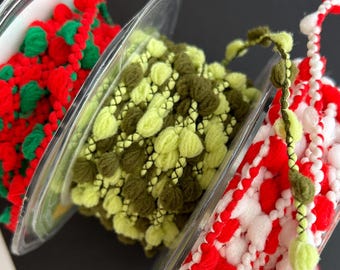 May include: Three spools of trim with pom poms. The first spool has red and green pom poms. The second spool has green and brown pom poms. The third spool has red and white pom poms.
