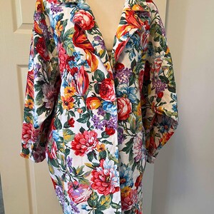 May include: A floral print blazer featuring a vibrant mix of red, pink, blue, yellow, and purple flowers on a white background. The blazer has a classic collar and long sleeves, offering a colorful and eye-catching design.