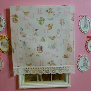 Può includere: Un muro rosa con una finestra bianca e una bordura in pizzo bianco. La finestra ha una cornice bianca e un vetro bianco. Ci sono otto piccole immagini incorniciate sul muro, ognuna con un'immagine diversa di un coniglio o di un altro animale. Le immagini sono tutte in uno stile simile e hanno uno sfondo bianco. Le immagini sono disposte in modo simmetrico attorno alla finestra.