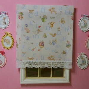 Può includere: Una finestra bianca con una bordura in pizzo e uno sfondo bianco con lettere blu e illustrazioni di animali. Ci sono otto cornici ovali con immagini di animali e bambini appese al muro.